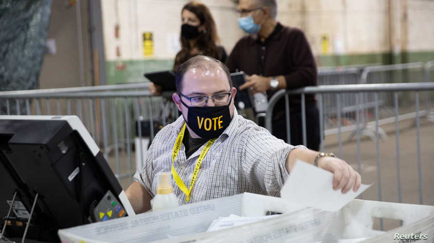 A poll worker tabulates ballots near observers at the Allegheny County Election Warehouse after the election in Pittsburgh,…