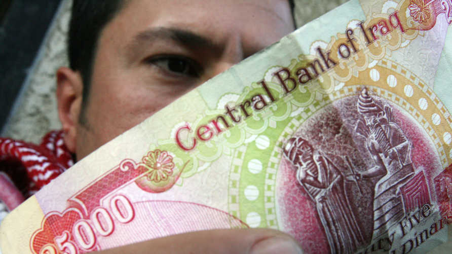 An Iraqi man checks the authenticity of a 25,000-dinar bill before using it in a shop in central Baghdad, 29 January 2008. It…