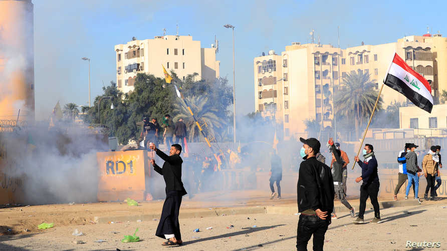 U.S. Embassy security men use tear gas to disperse protesters and militia fighters during a protest to condemn air strikes on…