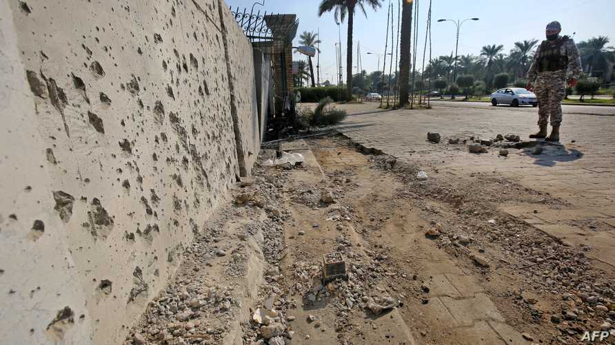 A member of the Iraqi security forces inspects the damage outside the Zawraa park in the capital Baghdad on November 18, 2020,…