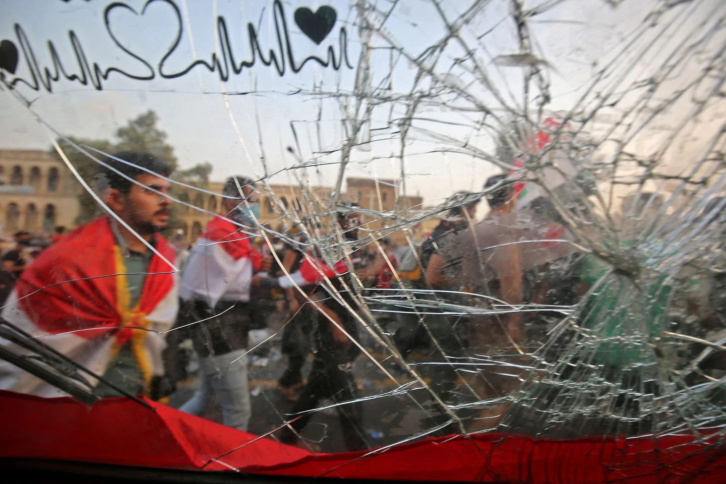 Protesters draped in national flags walk along al-Jumhuriya bridge, as seen from behind the broken windshield of a tuk-tuk. (Ahmad Al-Rubaye/Afp Via Getty Images)